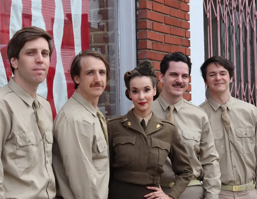 Ashley Anne and The Carnations in authentic 1940s USO-style uniforms in front of an American flag