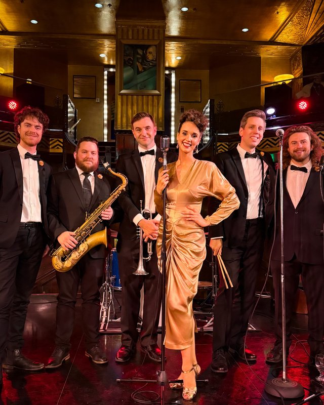 Ashley Anne in a gold satin gown with The Carnations in black tie on the Art Deco stage of the Cicada Club in Los Angeles